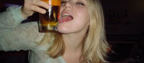 Mulher passando língua no copo de cerveja