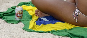Mulher com uma cerveja sentada numa canga do Brasil