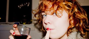 Mulher bebendo vinho com dedo na boca