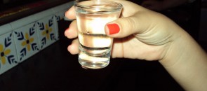 Mulher segurando um shot de cachaca