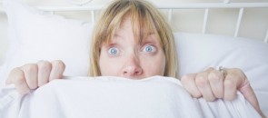Mulher deitada na cama e assustada