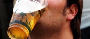 Homem segurando um copo de cerveja com a boca