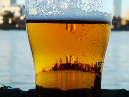 Copo de cerveja refletindo uma cidade