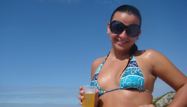 Mulher segurando copo de cerveja na praia