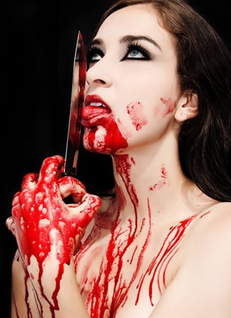Mulher cheia sangue lambendo uma faca