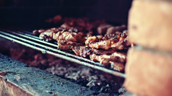 Churrasqueira acesa com carne sendo preparada