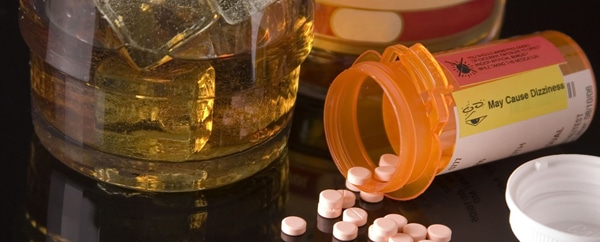 Álcool e Remédios - Copo de whisky com alguns remédios