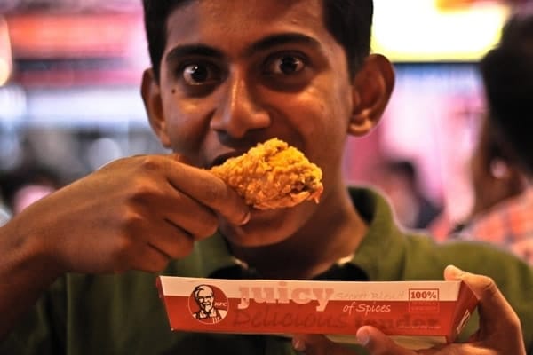 Garoto comendo frango kfc