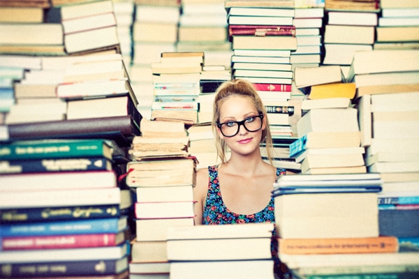 Menina cercada de livros por todos os lados