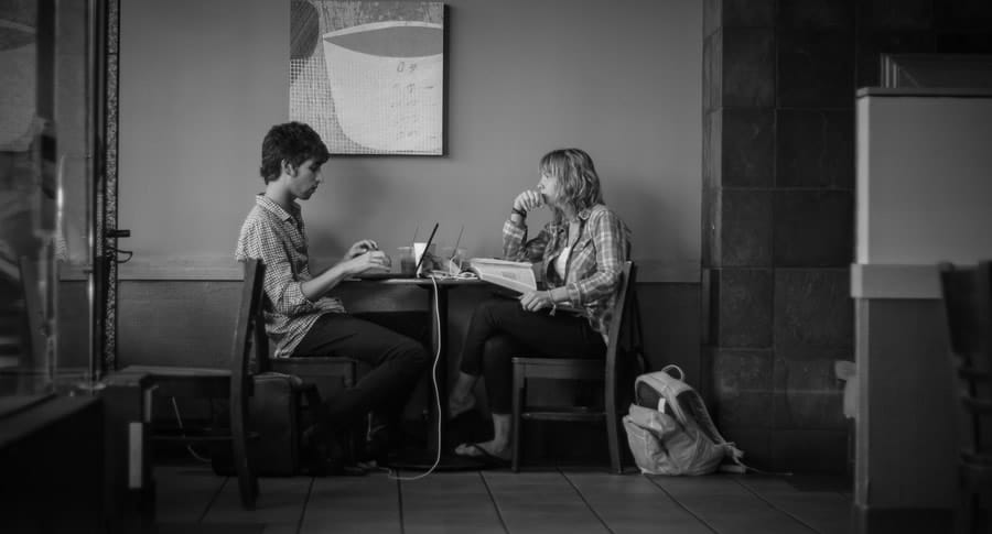 Casal sentado no bar com computador e conversando