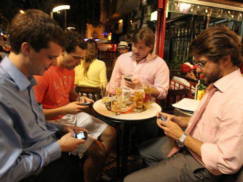 Homens no boteco conversando no celular