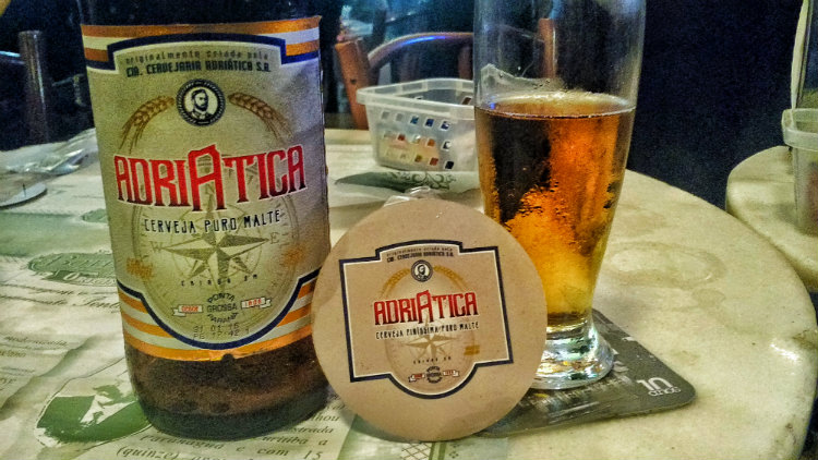 Garrafa, bolacha e copo da Adriática, uma cerveja para desbravadores