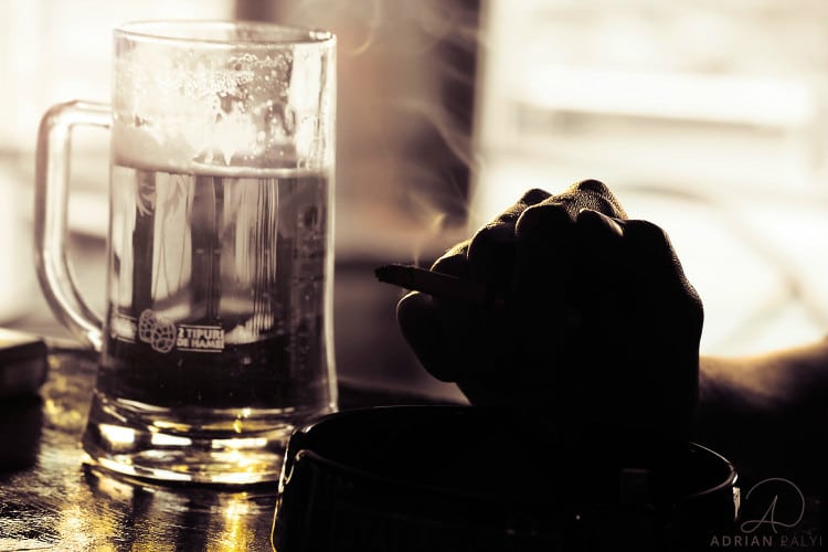 mão segurando cigarro e caneca de cerveja